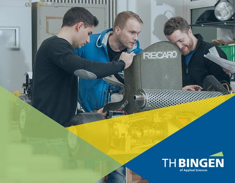 Three students working on a Recaro seat in a workshop, with the TH Bingen logo