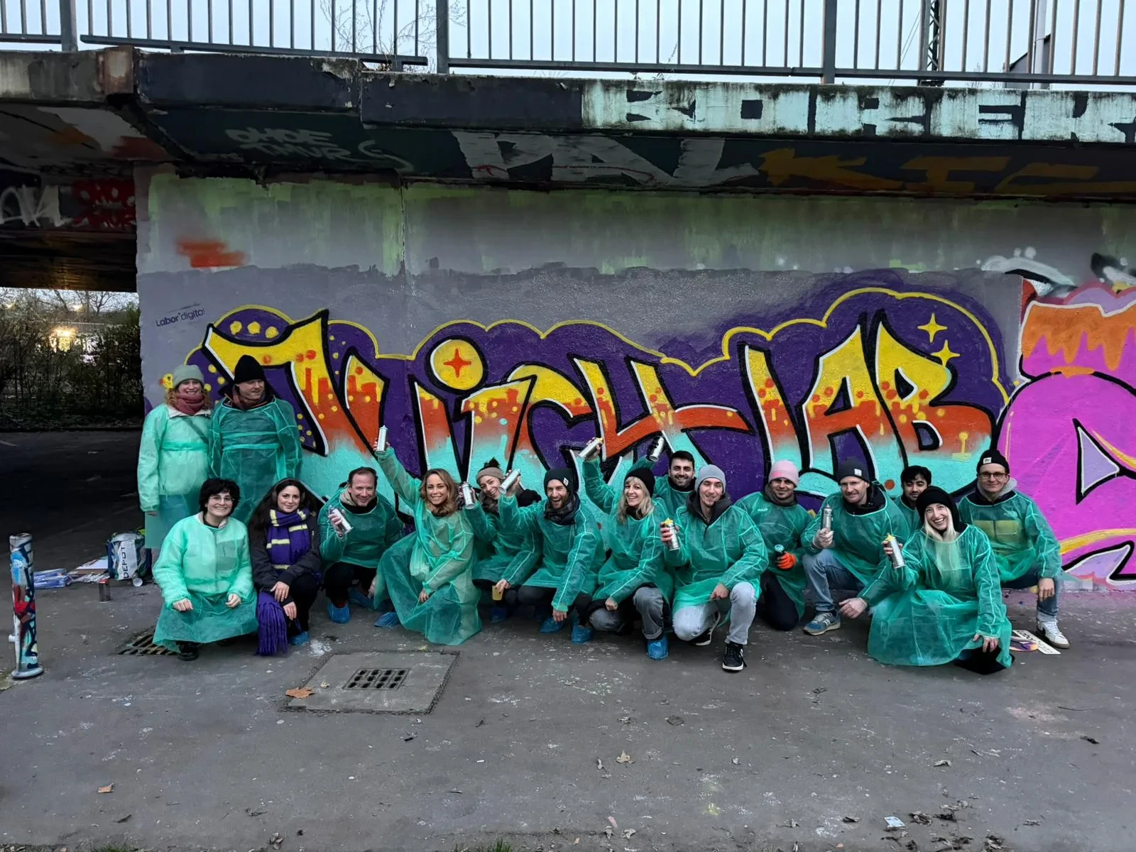 Das Team in Schutzanzügen vor seinem Graffiti
