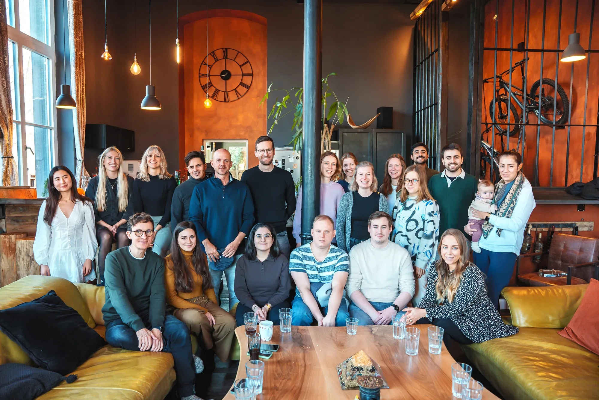 Das ganze Team in einer Lounge unter einer großen Uhr